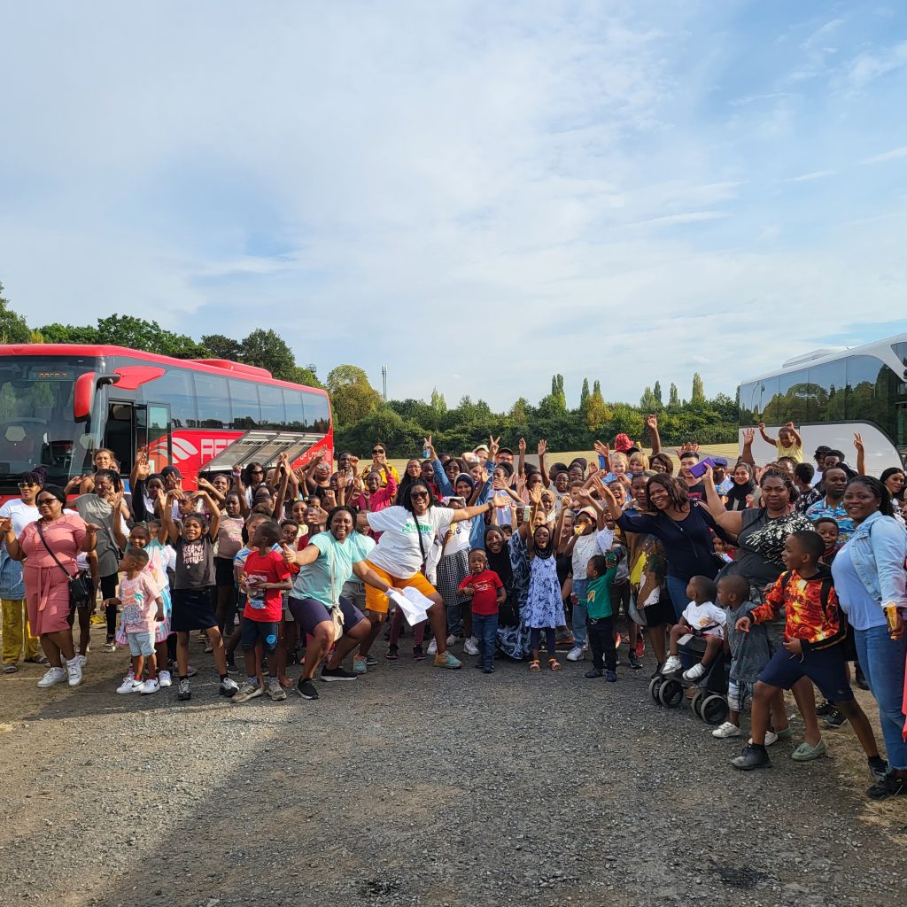 A large group of children stand in front of a coach in the carpark at Drayton Manor