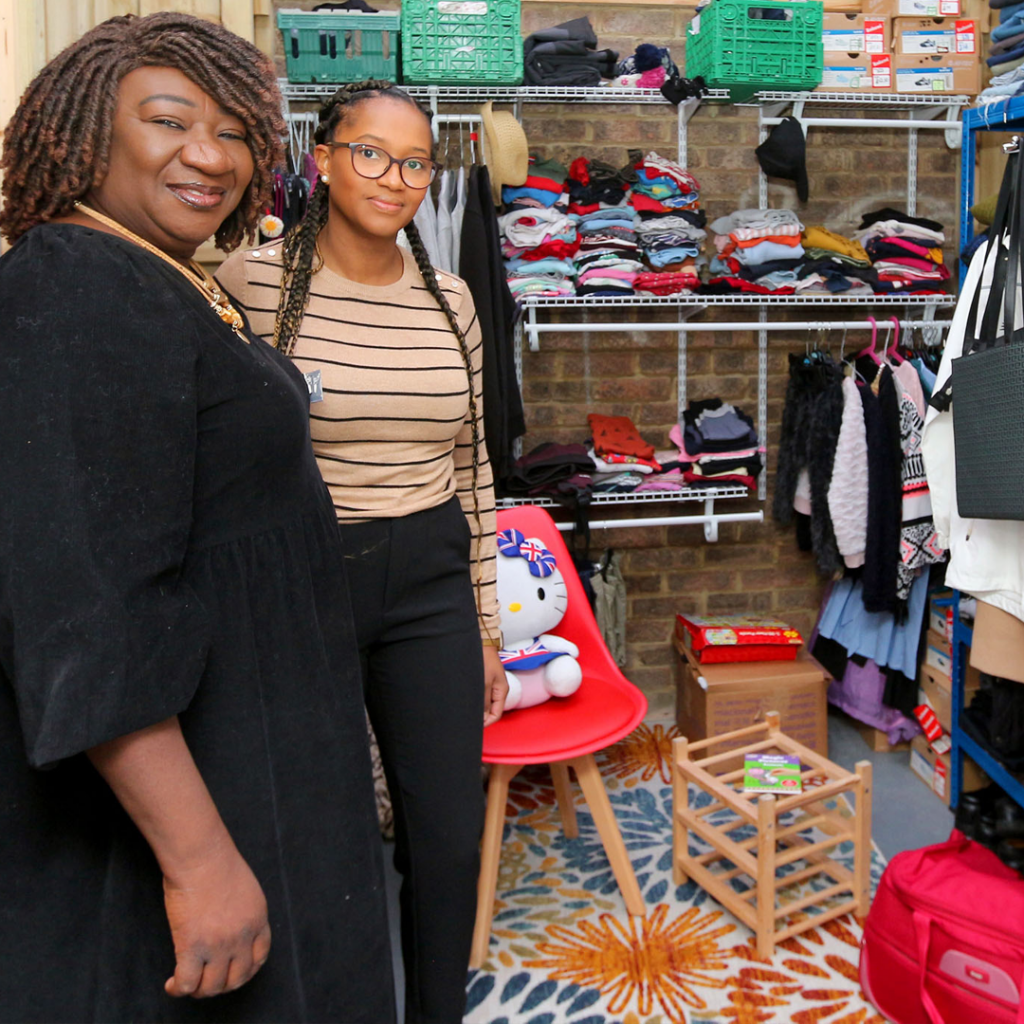 Two women standing surrounded by donated clothes